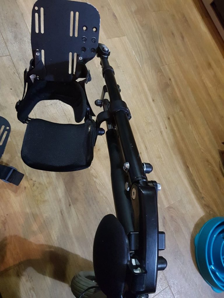 A black legrest extends from the wheelchair up the photo, with the footrest at the top and a black calf-pad underneath it.