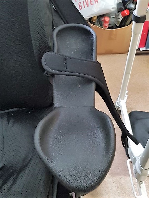 A black armrest for the wheelchair, which is demonstrably a deep channel, with a ridged pad at the far end to support the elbow and a large spread out area for supporting the palm of the hand,