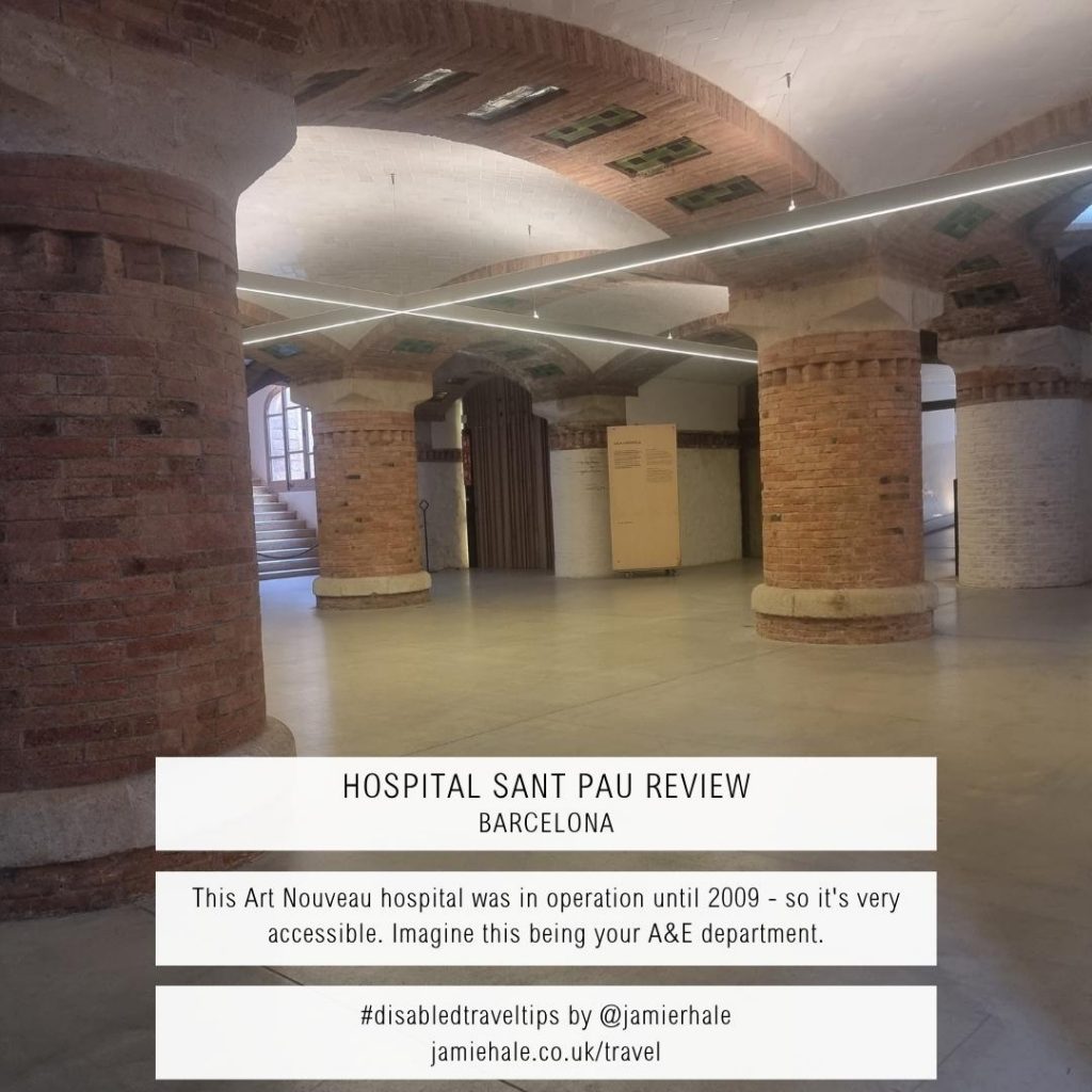 A photo taken inside Sant Pau Hospital of a large, open room with thick brickwork pillars and brickwork arches running along the ceiling between them. Text superimposed over the top reads 'Hospital Sant Pau Review Barcelona', 'This Art Nouveau hospital was in operation until 2009 - so it's very accessible. Imagine this being your A&E department.' '#disabledtraveltips by @jamierhale jamiehale.co.uk/travel'
