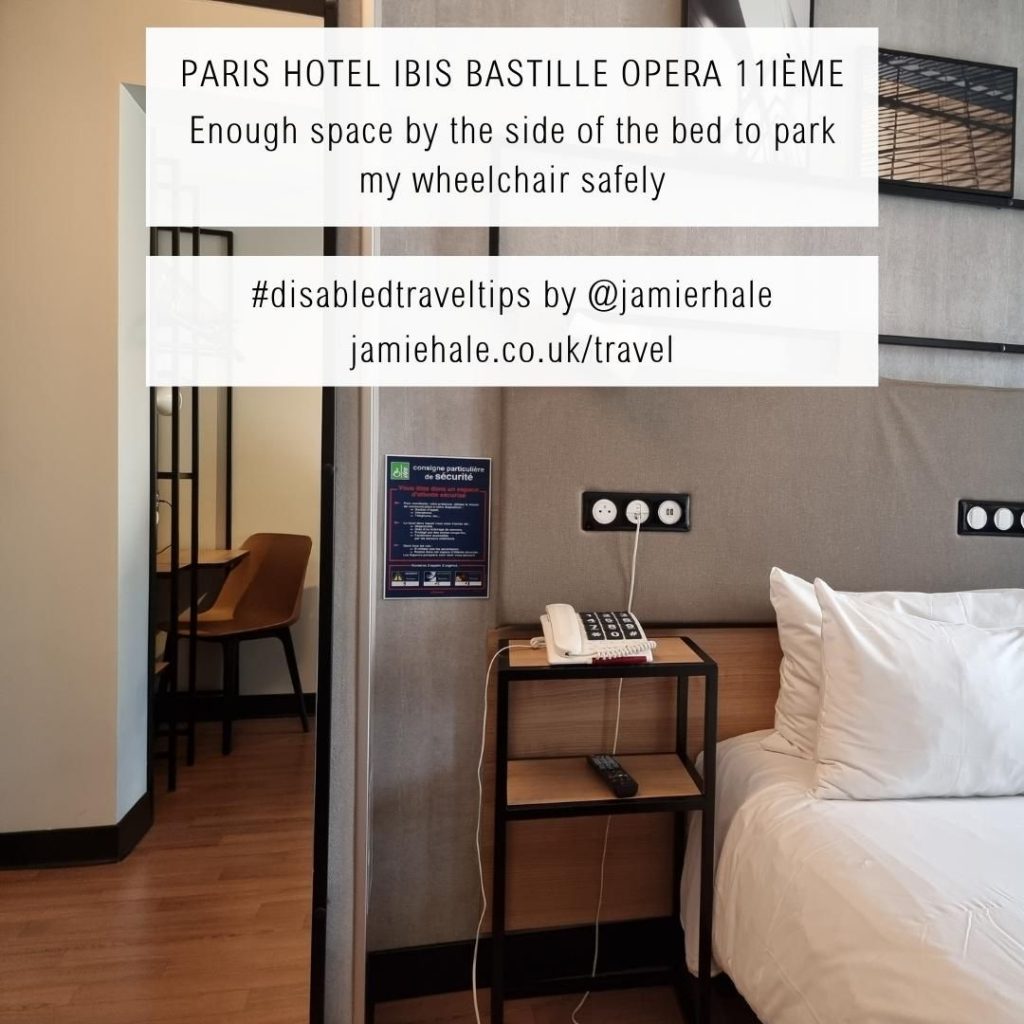 Superimposed on top of a picture of a hotel room showing the side of a bed, a bedside table, and a mirror with a desk in is the text "Paris (Hotel Ibis Bastille Opera 11ième, the coat hangers and clothing rail were too high, but I fitted under the desk nicely #DisabledTravelTips by @jamierhale jamiehale.co.uk/travel"