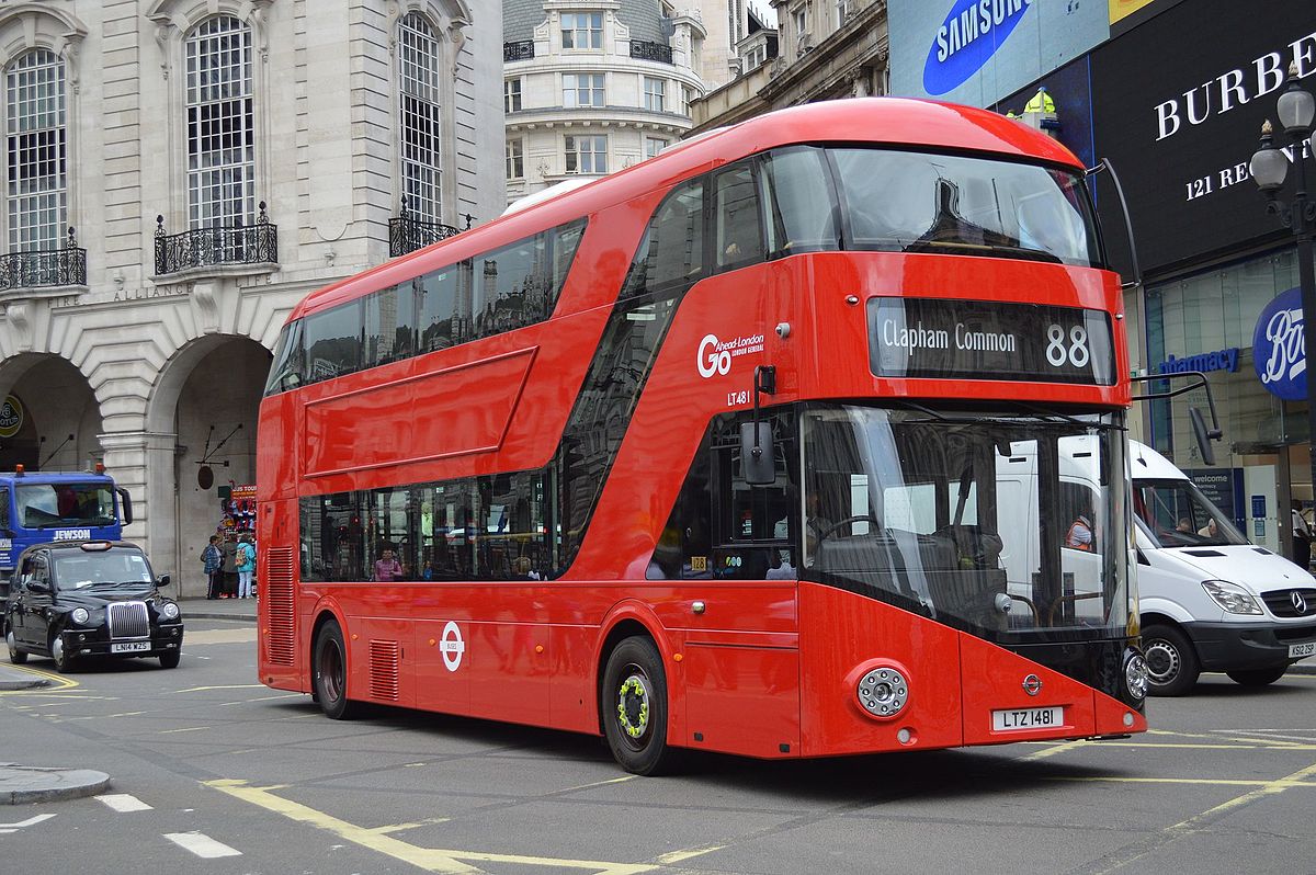 The photo is of a red Routemaster bus in London. The bus is number 88, to Clapham Common. It fills the image, and is on a road. In the background of the image are some shops, and the bus is being followed by a taxi