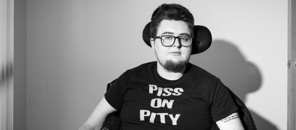 Jamie in black and white, wearing a "PISS ON PITY" t-shirt