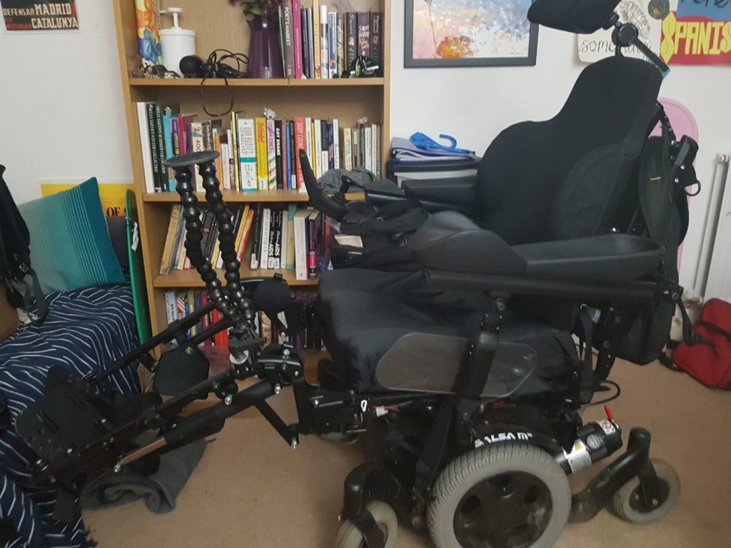 The same electric wheelchair in the same place with the legrests extended as far as possible
